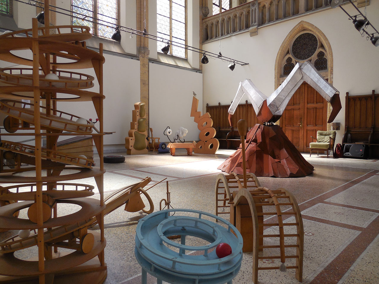 Tentoongestelde objecten in een ruime en hoge neogotische kapel.